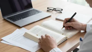 Researcher compares an open book with source papers to assess whether its citations support key claims.